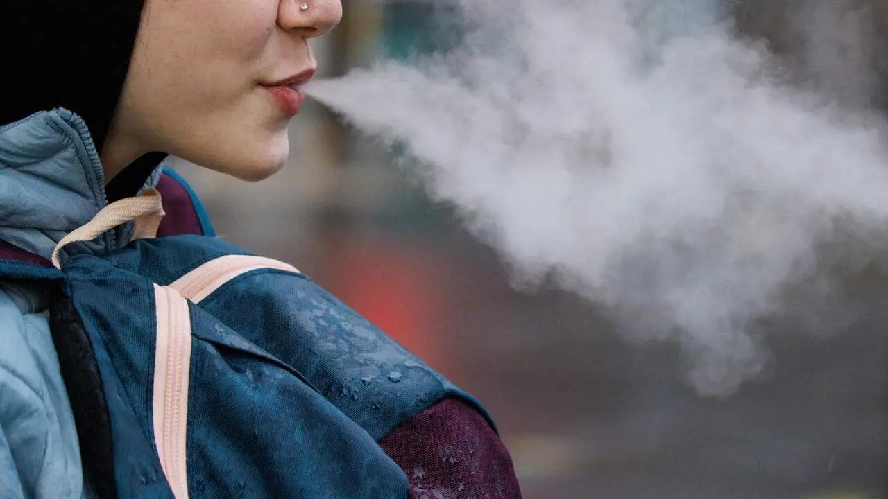 Una joven expulsa humo de un vapeador. EFE