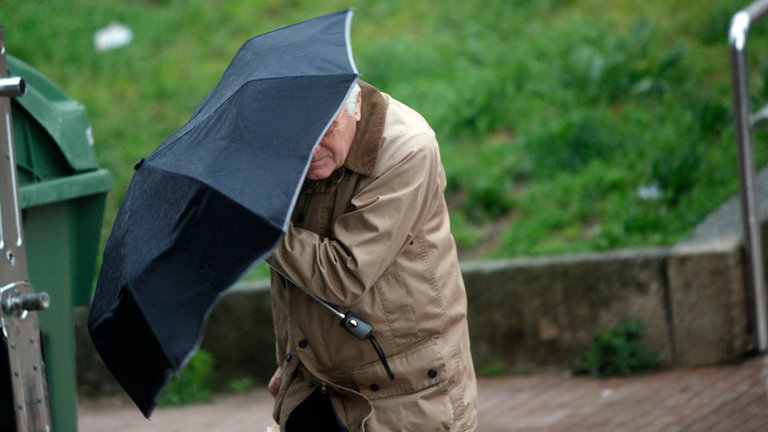 El viento pone en apuros a un hombre para mantener el paraguas. JAVIER CERVERA