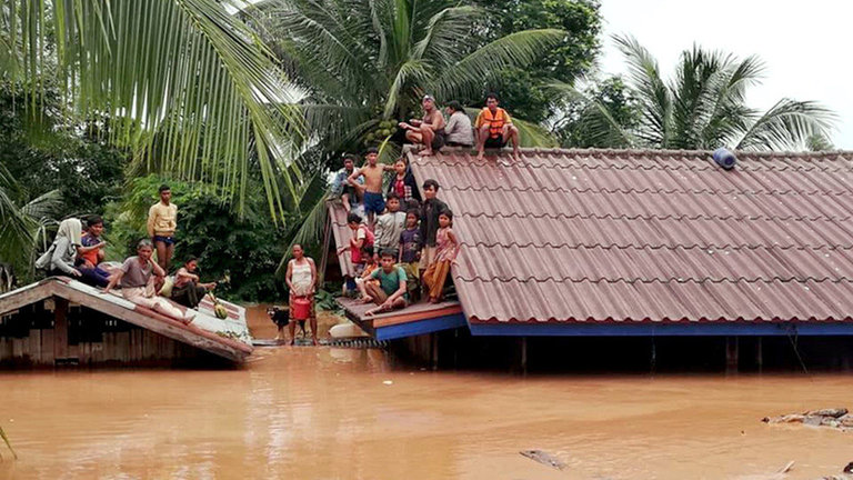 Unos supervivientes de la inundación huyen del agua al subirse a los tejados de las casas de la aldea. EFE