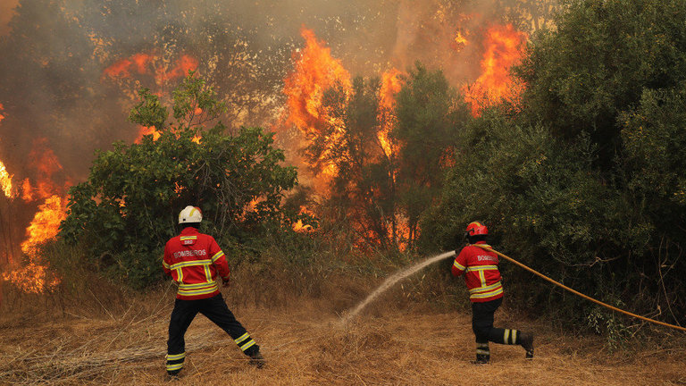 Bomberos tratan de extinguir las llamas del incendio declarado en el área de Monchique en el Algarve. MIGUEL A. LOPES (EFE)