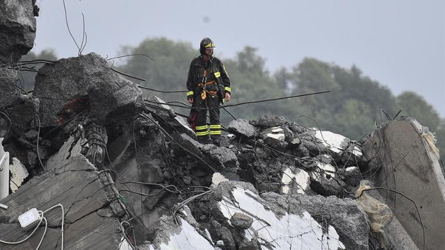 Un bombero permanece sobre los escombros del puente derrumbado en Génova. EFE