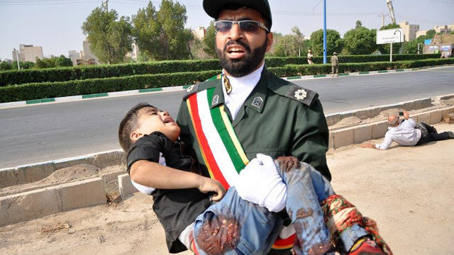 Un soldado iraní carga en brazos con un niño que resultó herido en el atentado terrorista contra un desfile militar en Irán. BEHRAD GHASEMI (EFE)