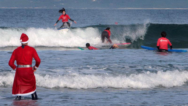 Cientos de Papás Noel llegan surfeando un año más a una playa de Pontevedra. SALVADOR SAS