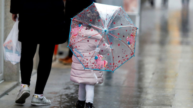 Una niña con un paraguas camina acompañada de su madre por una calle de Lugo. ELISEO TRIGO