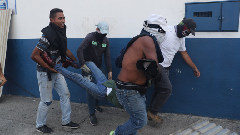 Cuatro simpatizantes de Guaidó ayudan a un herido tras las protestas.MIGUEL GUTIÉRREZ (Efe)