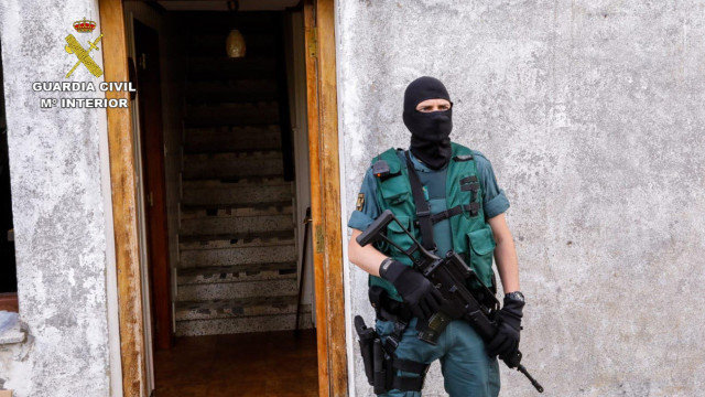 Un agente del operativo desplazado a Galdo, en Viveiro, apostado ante la casa de la detenida. EFE