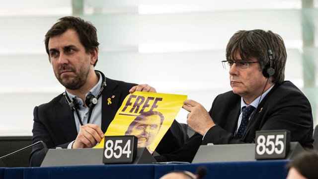 Toni Comín y Carles Puigdemont muestran una foto de Oriol Junqueras en el Parlamento Europeo. PATRICK SEEGER (Efe)