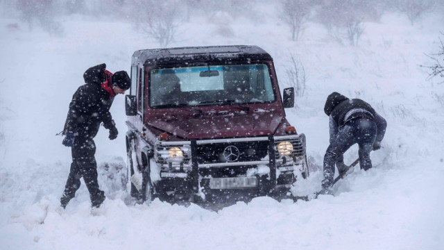 Dos hombres intentando sacar su vehículo atrapado en la nieve este lunes en Murcia. EFE