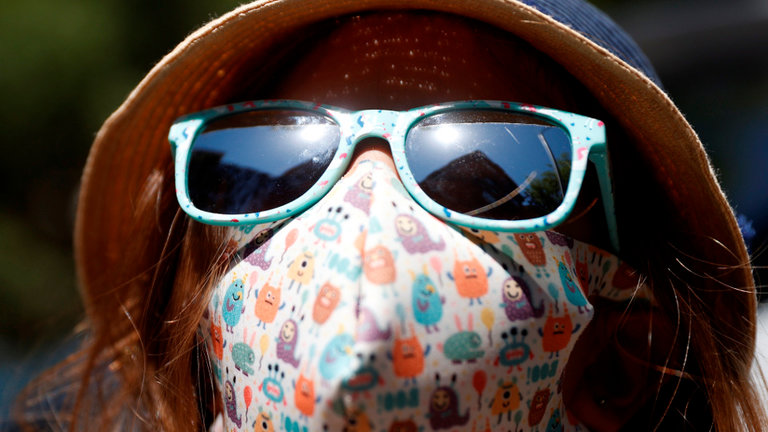 Unha nena con máscara e con chapeu para protexerse da calor. MARISCAL (EFE)