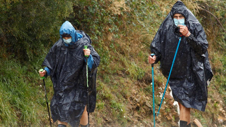 Dous peregrinos protéxense da choiva coas súas chubasqueros ao seu paso polo Cebreiro. EFE