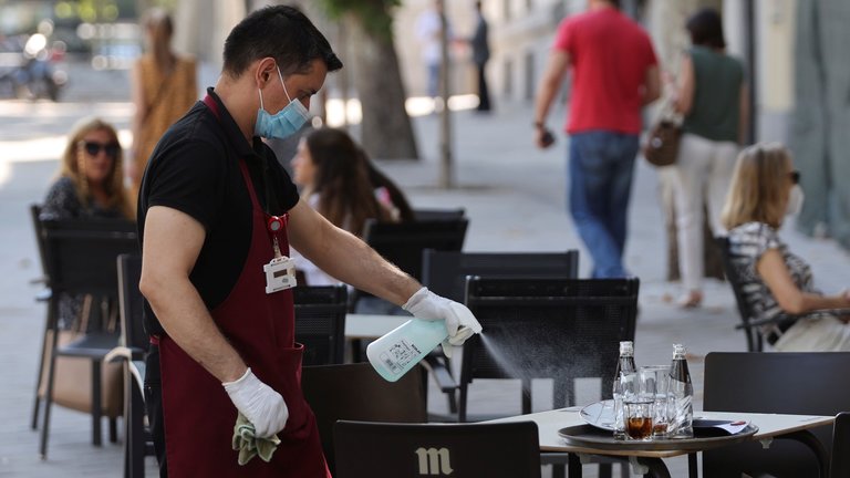 Un camarero desinfecta una mesa en un bar del centro de Madrid. MARISCAL (EFE)