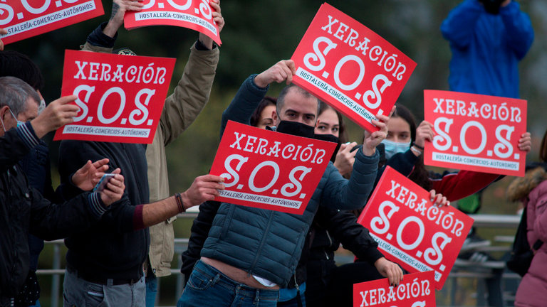 Un grupo de hosteleros, autónomos y pequeños comerciantes de Ourense realizaron una protesta durante el paso del pelotón de La Vuelta, este miércoles. BRAIS LORENZO (EFE)