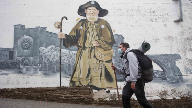 Un peregrino pasa por delante del mural del Zapatones, en el Camino Francés. EUROPA PRESS