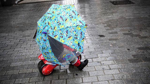 Un neno protéxese da choiva baixo un paraugas. VILLAR LÓPEZ (EFE)