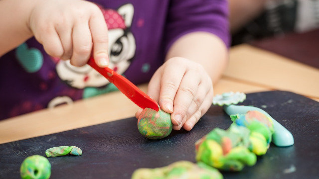 Unha nena xoga con plastilina nunha gardería. EP