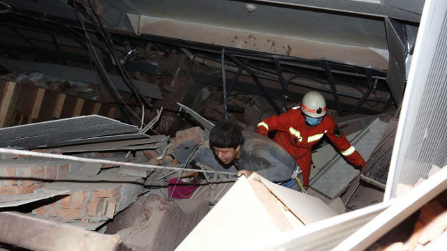 Un efectivo do equipo de rescate axuda a saír a un home de entre os cascallos. XIAO FAN (Efe)