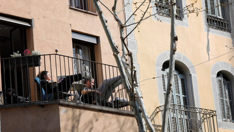 Ciudadanos tomando el sol en su balcón durante el confinamiento. SUSANNA SÁEZ (EFE)