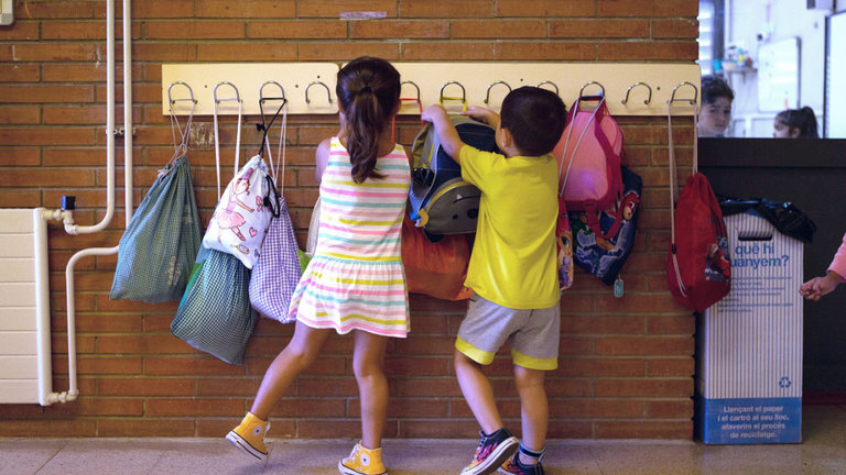 Dos niños cuelgan sus mochilas. EFE