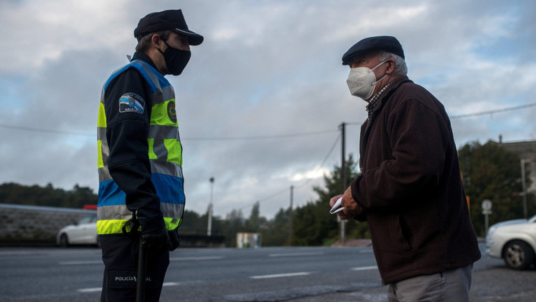 Un agente de Policía Local habla con un hombre, durante un control de movilidad, realizado a la entrada la localidad de O Carballiño. EFE
