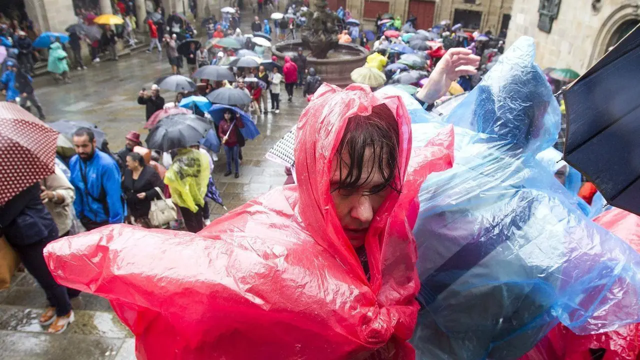 Dos turistas se protegen de la lluvia con chubasqueros desechables
