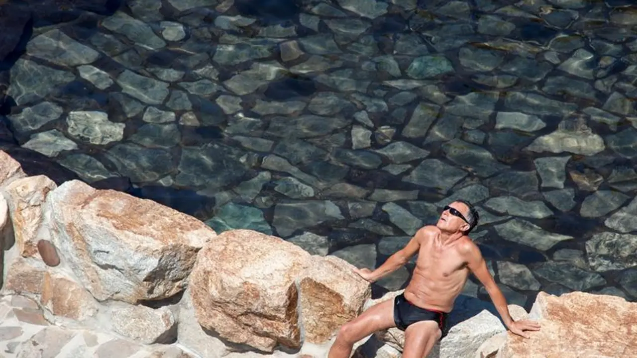 Un hombre toma en sol en una zona fluvial del río Miño en Ourense