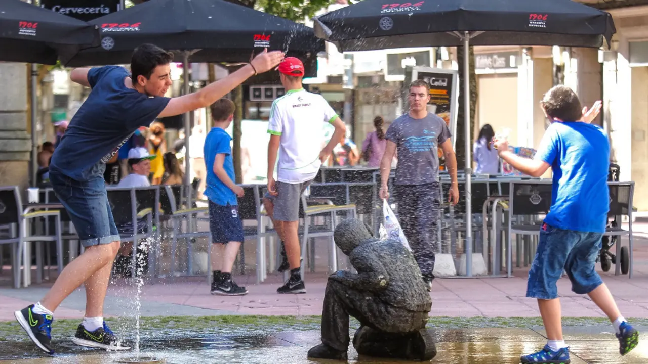 J&oacute;venes juegan y se refrescan en una de las fuentes de la ciudad