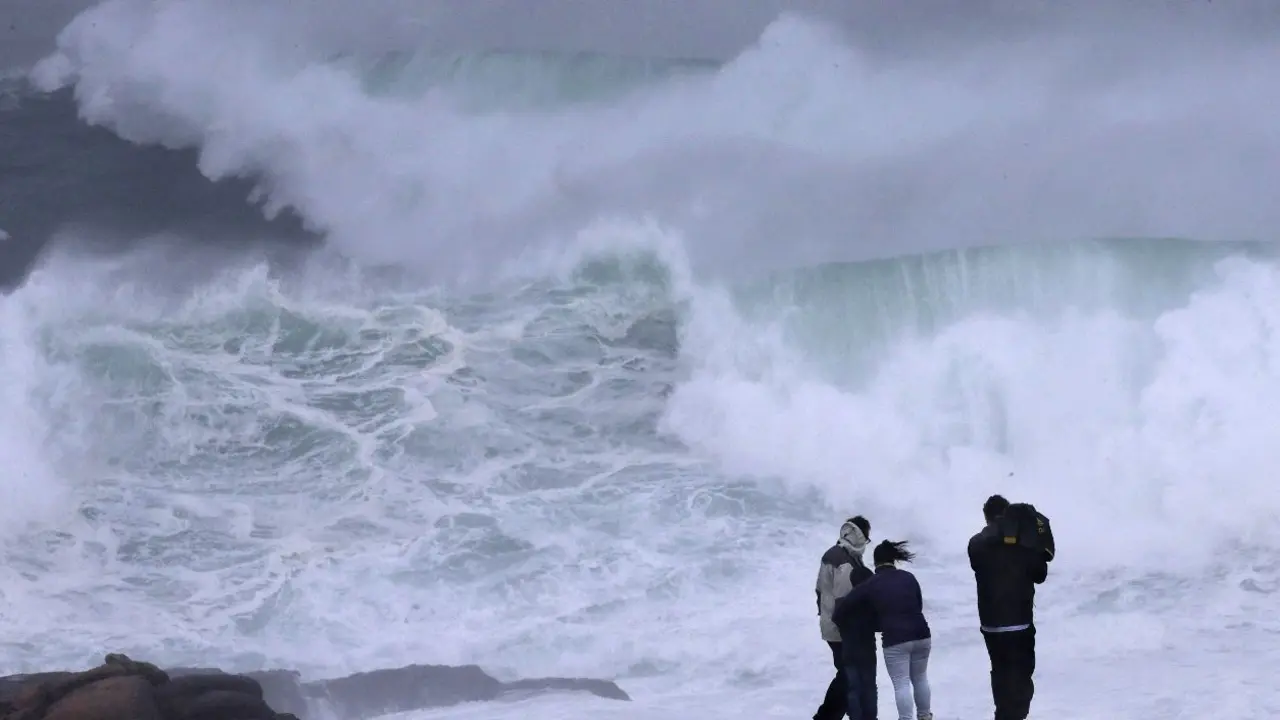 Varios turistas observan las olas en Muxía