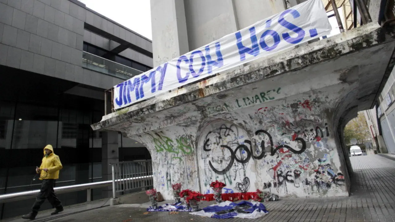 Velas, banderas y flores bajo una pancarta con el lema "Jimmy con nós". AEP