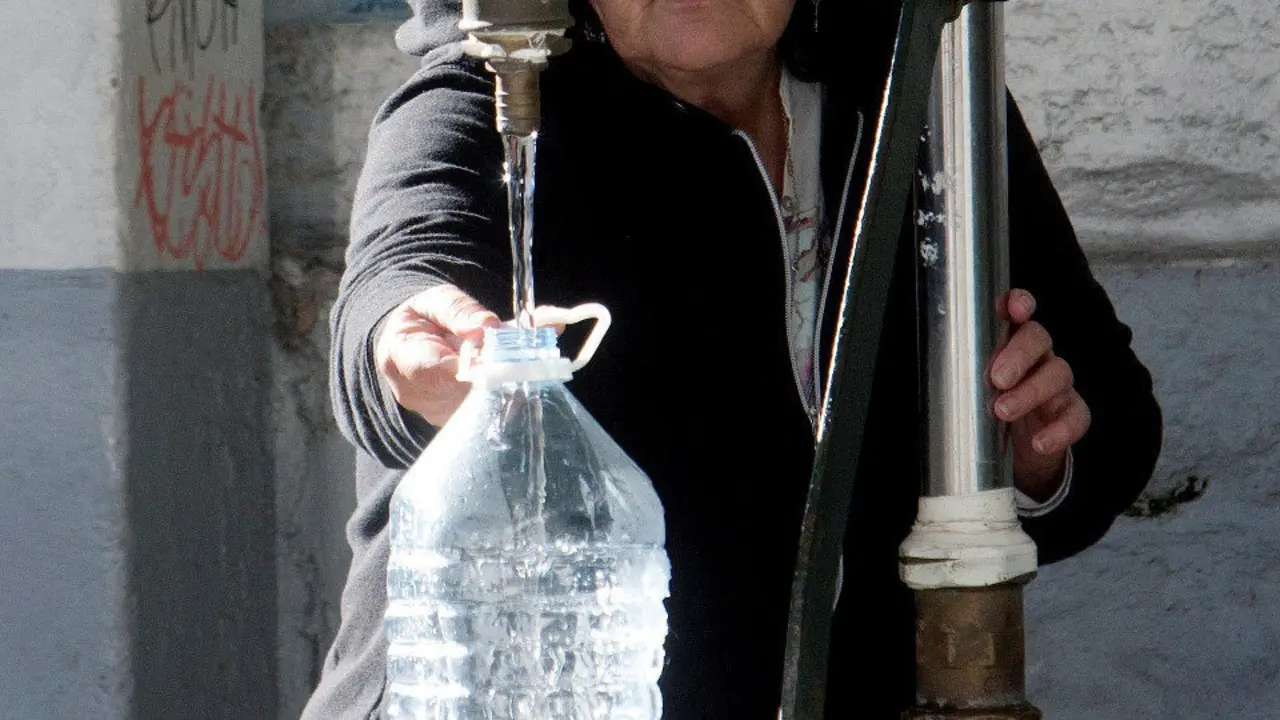 Una vecina de Vigo se abastece de agua potable en una fuente pública. SALVADOR SAS (EFE)