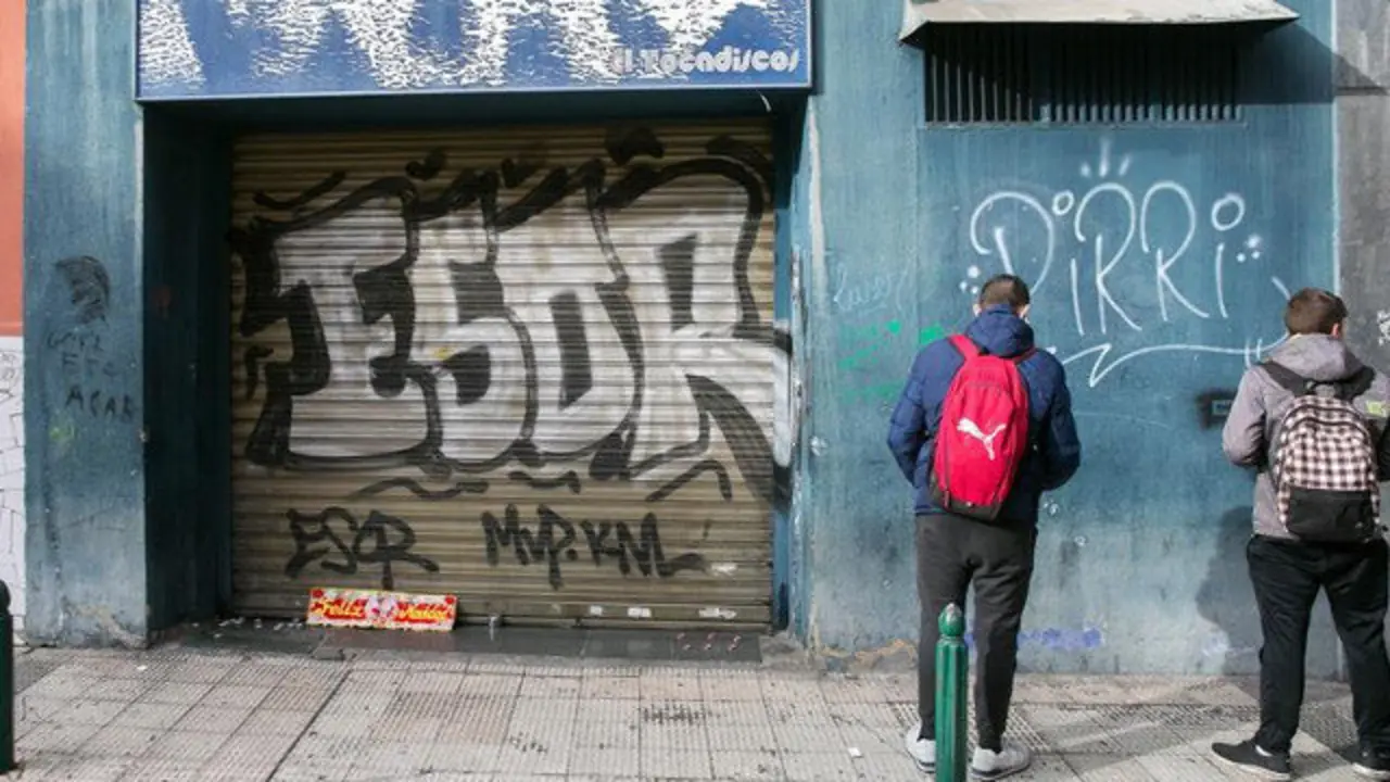 Unos jóvenes miran la puerta del bar a cuyas puertas fue agredido Víctor Laínez. JAVIER CEBOLLADA (EFE)