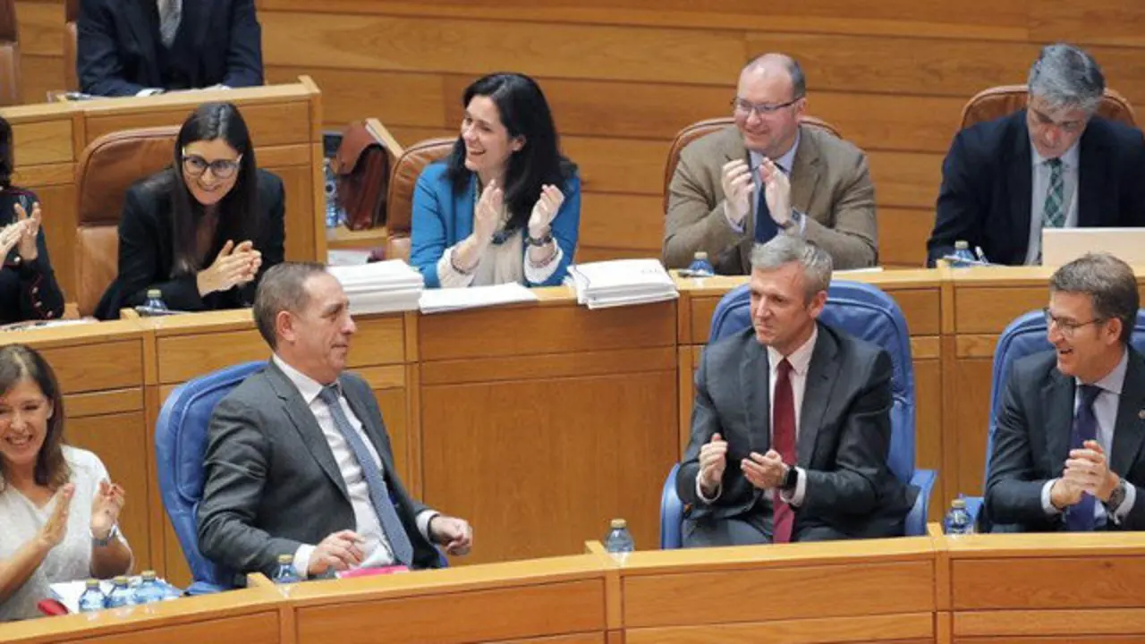 Feijóo (d) y los diputados del PP apluaden al conselleiro de Hacienda, Valeriano Martínez. LAVANDEIRA JR. (EFE)
