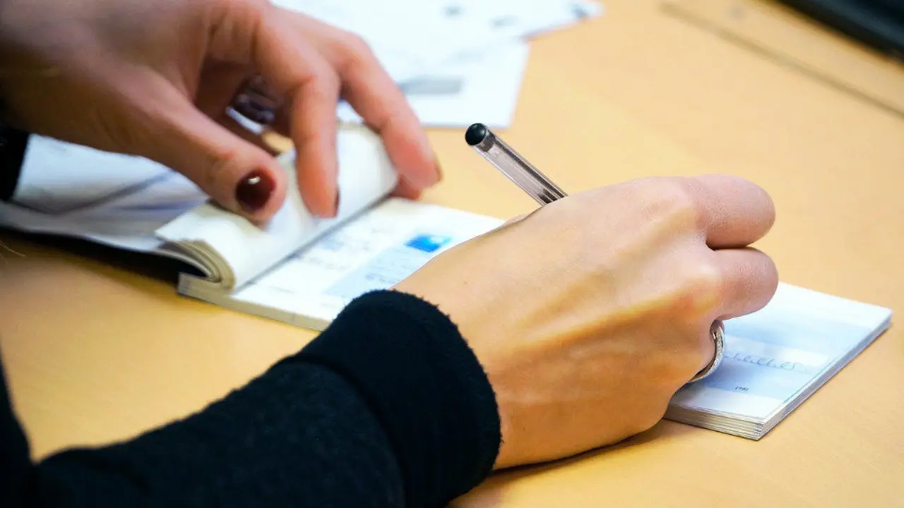 Una mujer extiende un cheque. EP