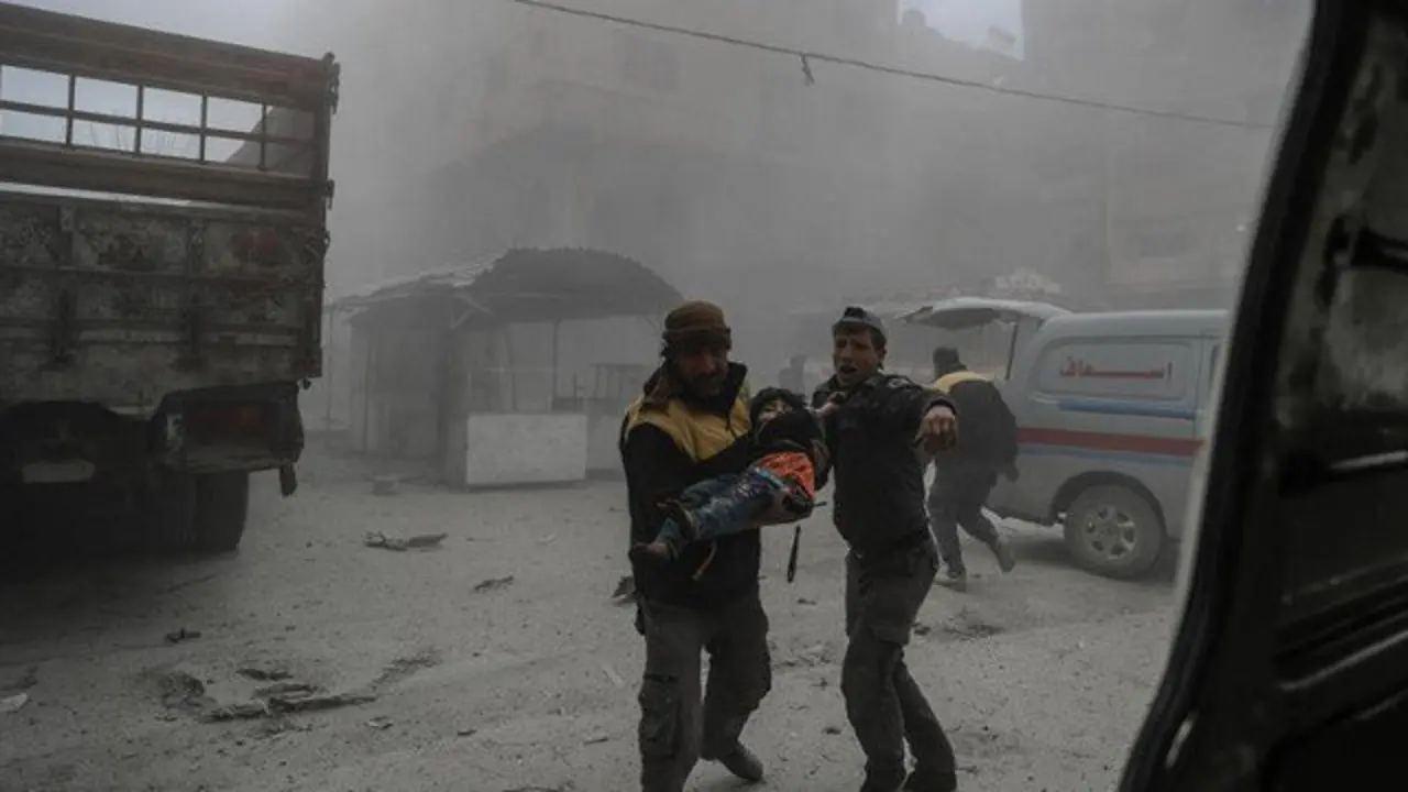 Un voluntario de los Cascos Blancos lleva a un niño herido en brazos hasta una ambulancia, Guta Oriental, Siria. MOHAMMED BADRA (EFE)