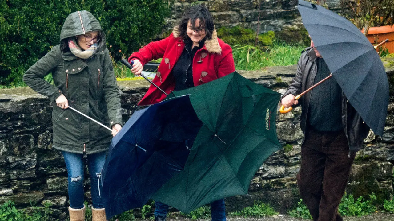Dos mujeres luchando contra el viento con sus paraguas. AEP