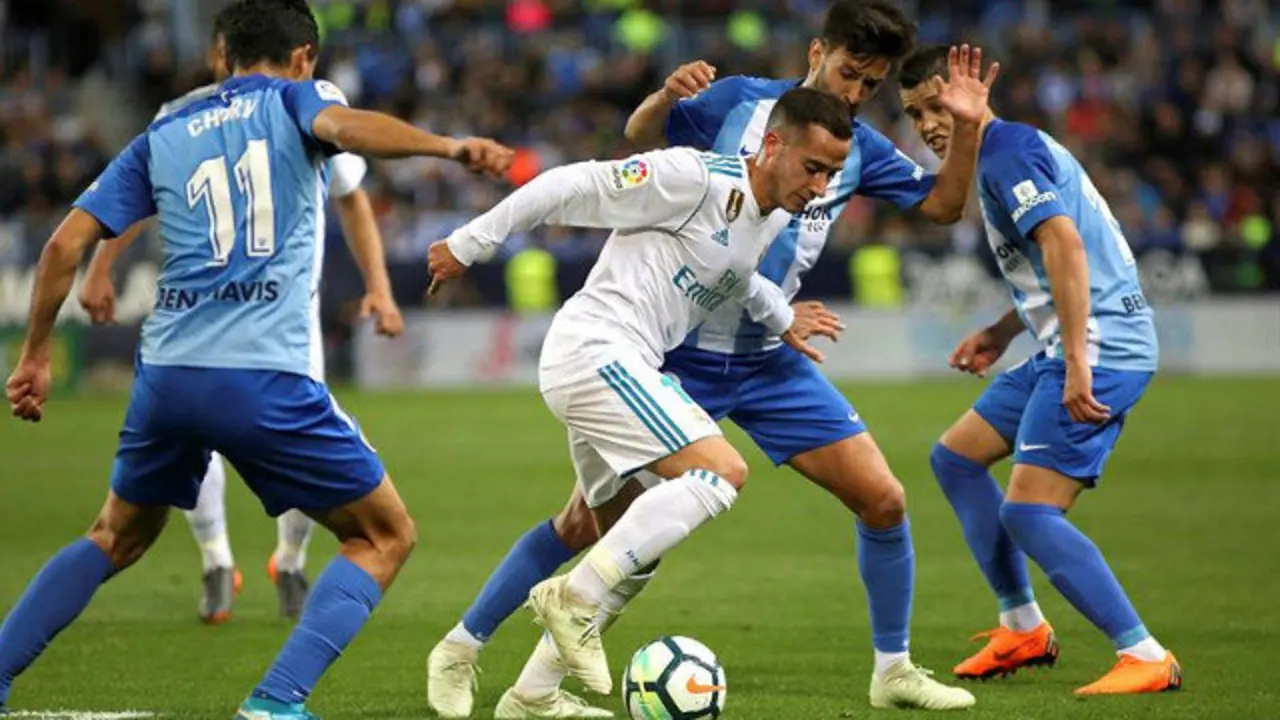 Lucas Vázquez intenta llevarse el balón ante los defensas del Málaga. DANIEL PÉREZ (EFE)