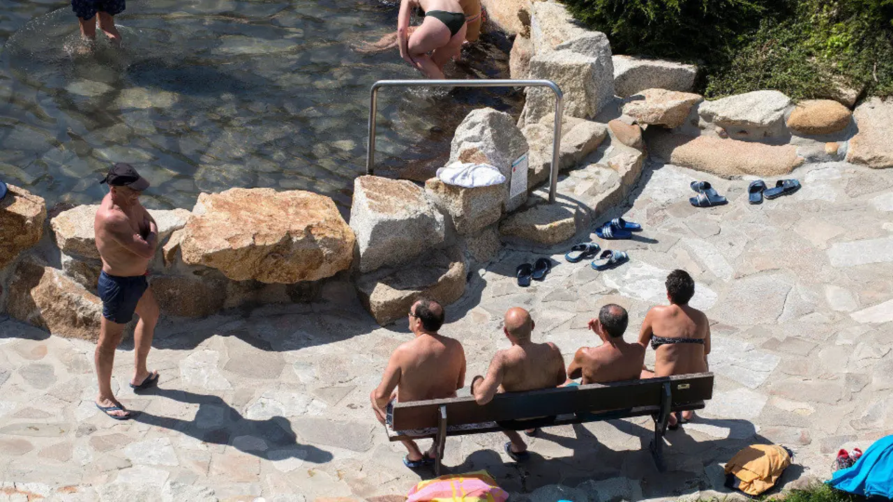 Varias persoas gozan do sol xunto ao río Miño en Ourense. EFE