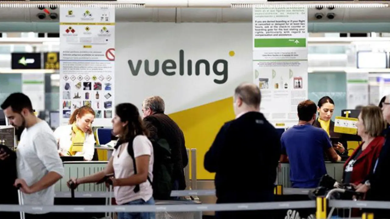 Un grupo de pasajeros ante un mostrador de facturación de Vueling. ALBERTO ESTÉVEZ (EFE)
