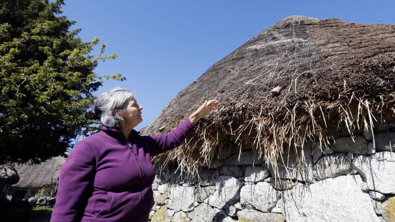 Una vecina enseña el estado en que se encuentra el tejado de una de las pallozas de Piornedo. XESÚS PONTE