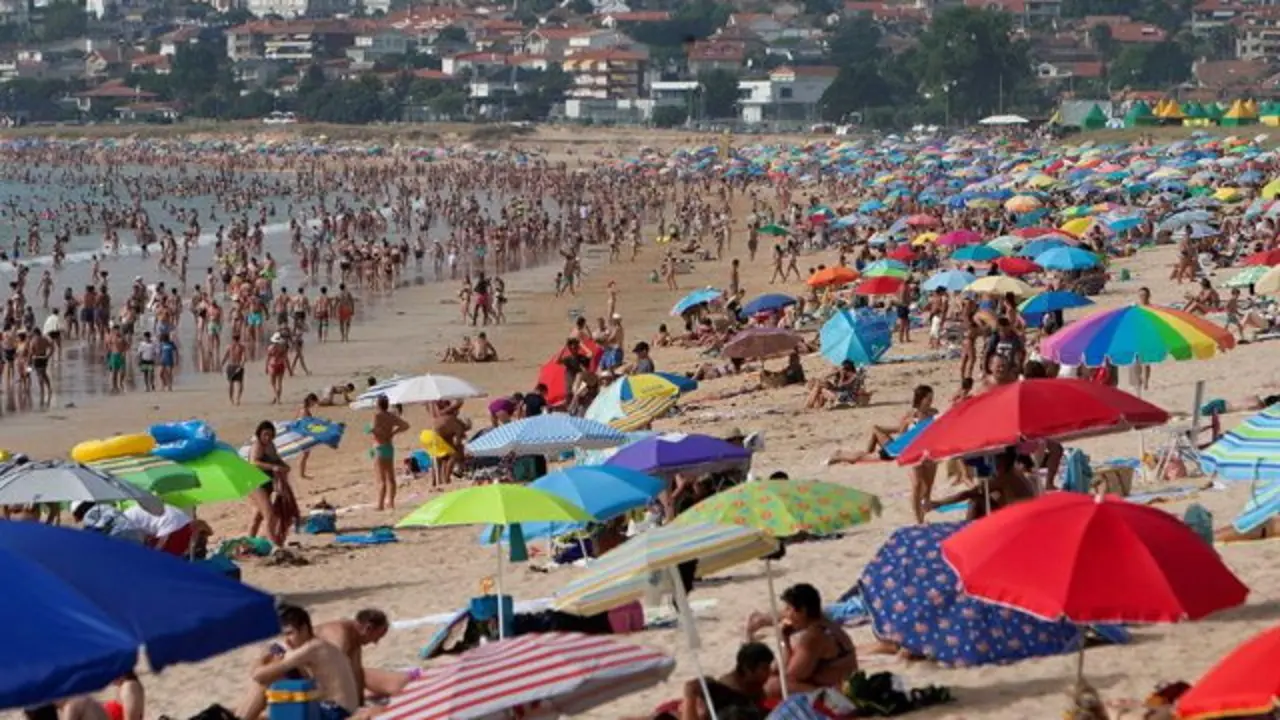Turistas y vecinos se refrescan en la Playa América en Nigrán. EFE