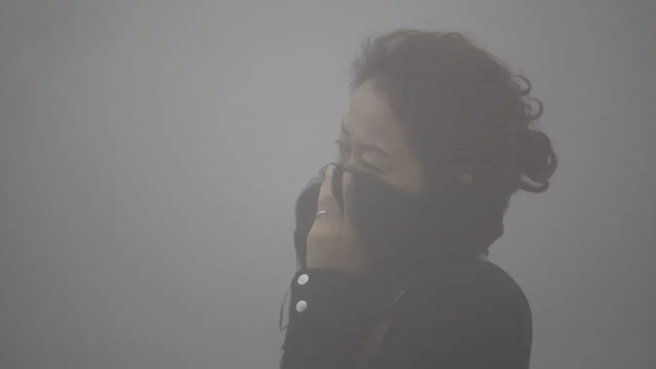 Una mujer se cubre la cara para atravesar una nube de contaminación en China. EFE