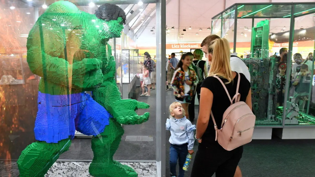 Unha familia diante dun superheroe feito con pezas de Lego. EFE