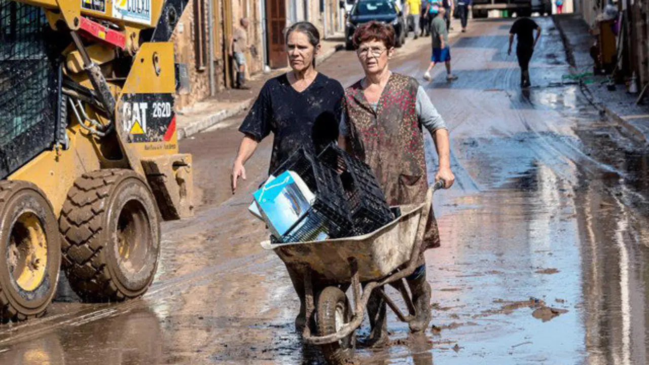 Varias personas limpian las calles tras la riada. CATI CLADERA