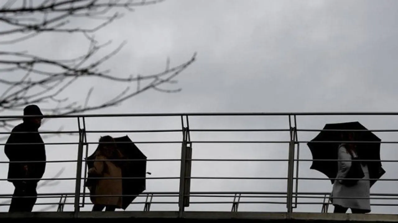 Varias personas se protegen del agua y del viento. LUIS TEJIDO