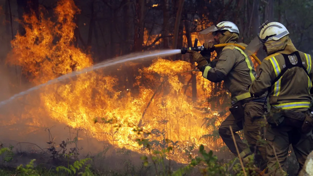 Dos bomberos apagan un foco del incendio de Rianxo.LAVANDEIRA 