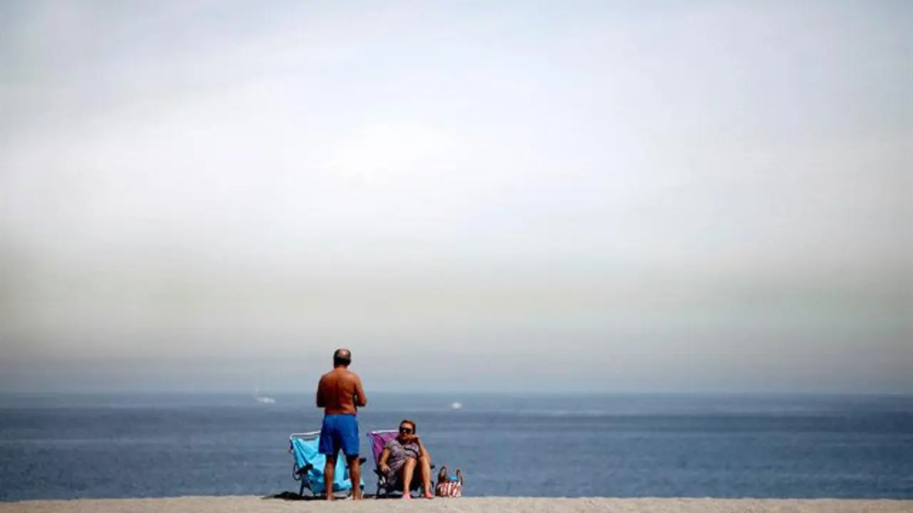 Gente en la playa con nubes. CABALAR (EFE)