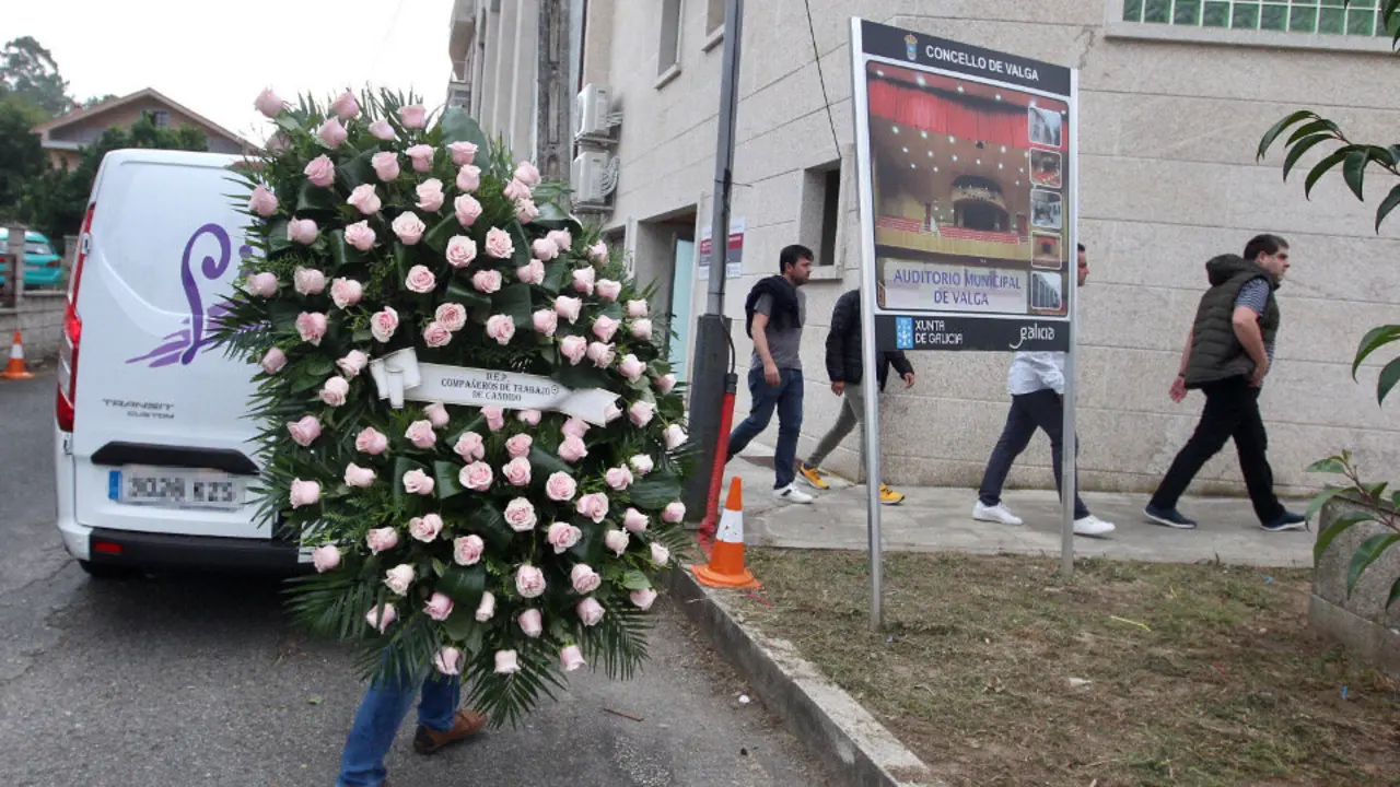 Un hombre carga con una corona de flores durante el velatorio de las tres mujeres. rafa fariña