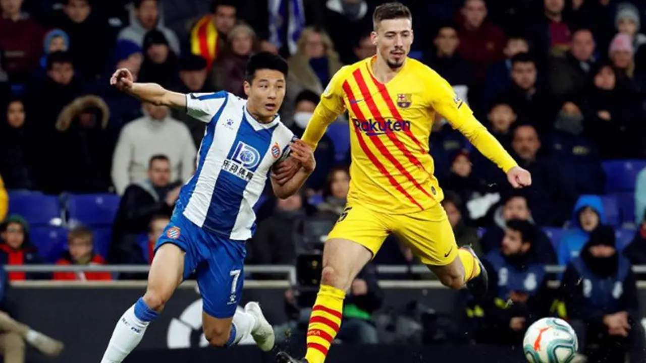 El delantero chino del RCD Espanyol Wu Lei (i) lucha con el defensa francés del FC Barcelona Clément Lenglet. TONI ALBIR
