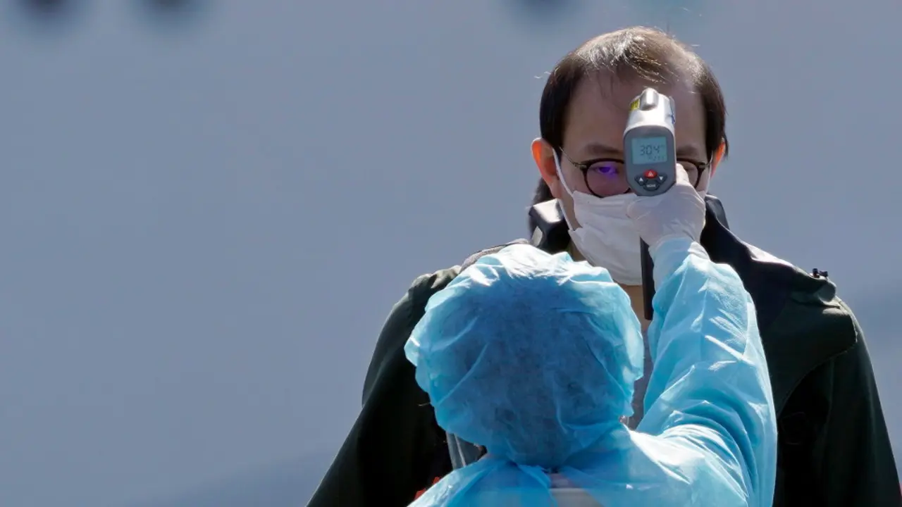 Una trabajadora toma la temperatura a un hombre como medida de prevención contra el coronavirus. EFE