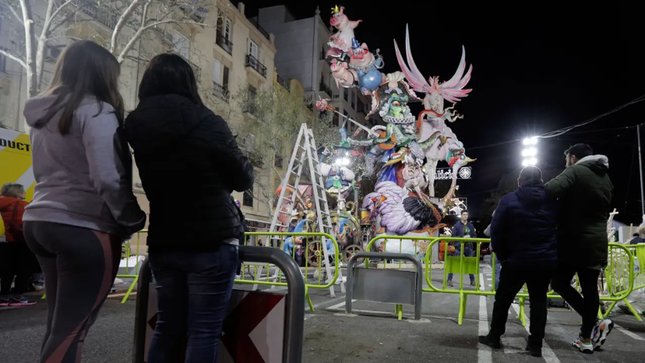 Unos j&oacute;venes observan una falla a medio montar en Valencia. EFE