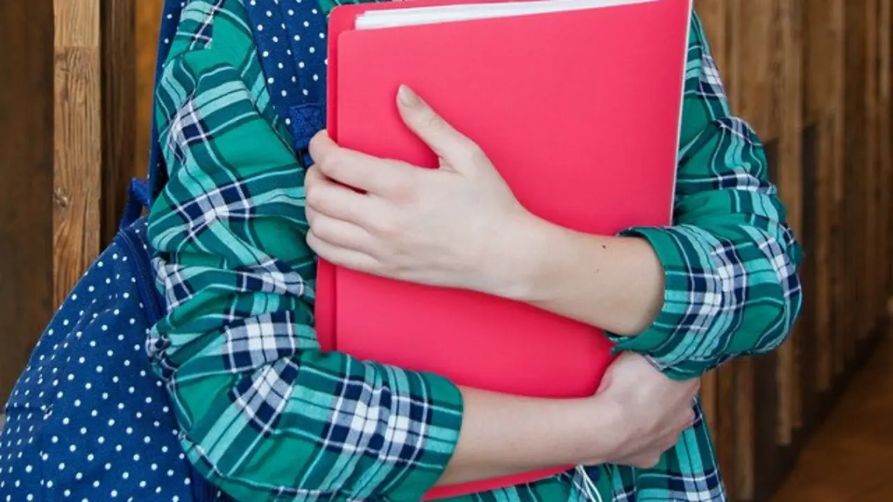 Una estudiante sostiene su carpeta.PIXABAY